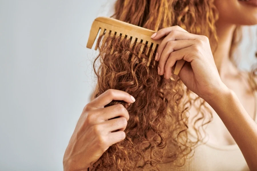 Woman with ginger hair combing through leave-in conditioner