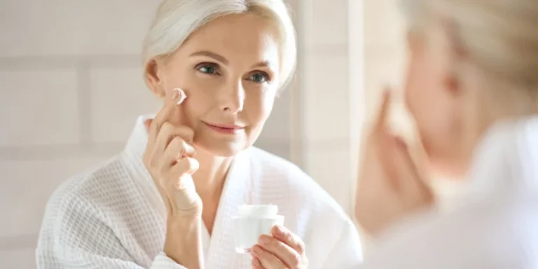 Woman with white hair applying anti aging cream to face