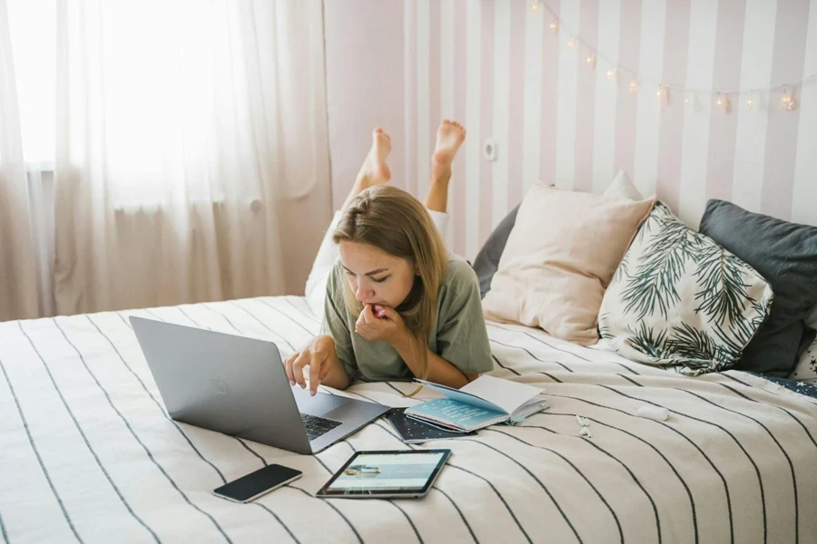 Woman working on her computer while lying in bed
