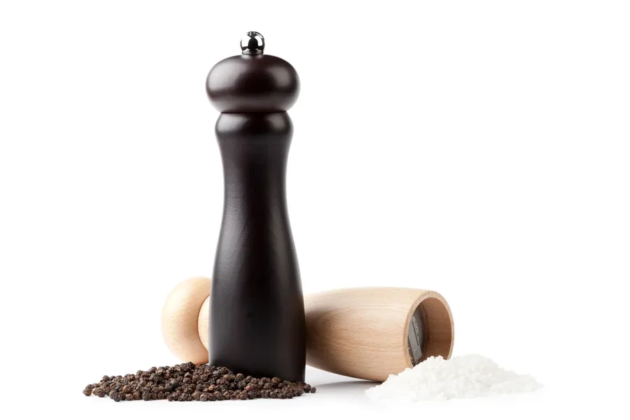 Wooden grinders with black pepper and pinch of salt