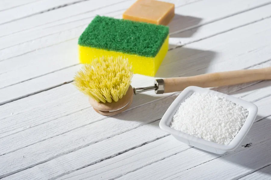 Yellow and green dish sponge next to bamboo dish brush