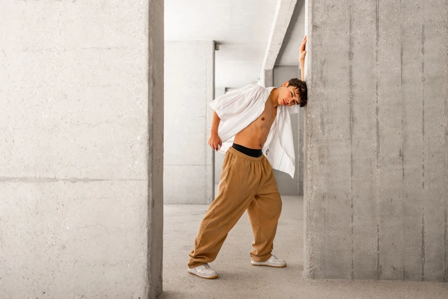 Young man in casual drawstring pants leaning on the wall