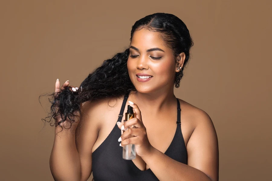Young woman applying hair mist to wavy hair