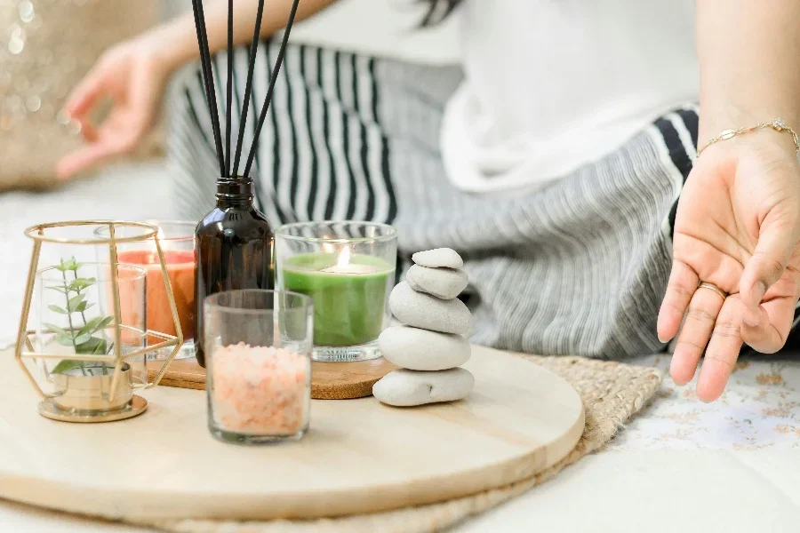 Mujer joven meditando con velas y aromas.