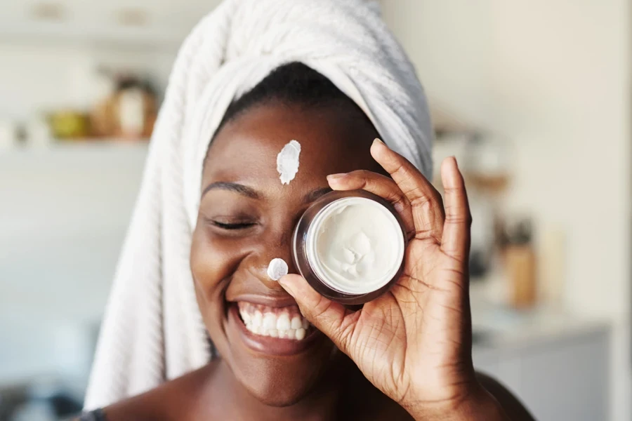 Young woman with dark spots holding jar of tretinoin cream