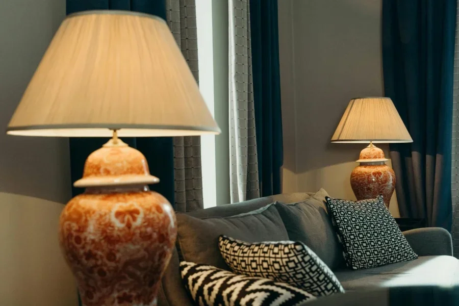 Диван с подушками между лампами возле штор