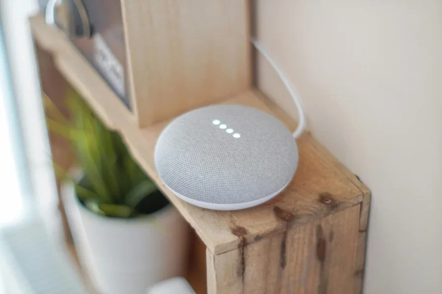 Un altavoz inteligente Google Home Mini en un estante de madera, que combina tecnología con decoración del hogar.