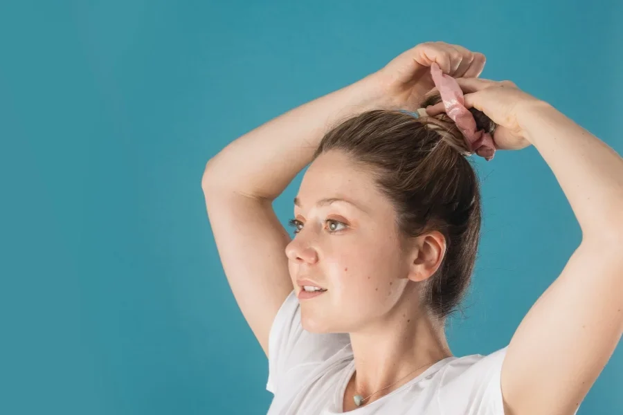 A Woman Putting Her Hair Up With A Pink Scrunchie