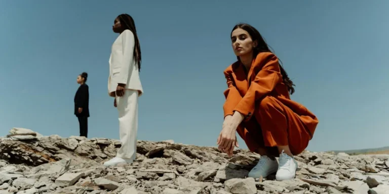 Seorang Wanita Berjas dan Celana Oranye Duduk di Atas Batu