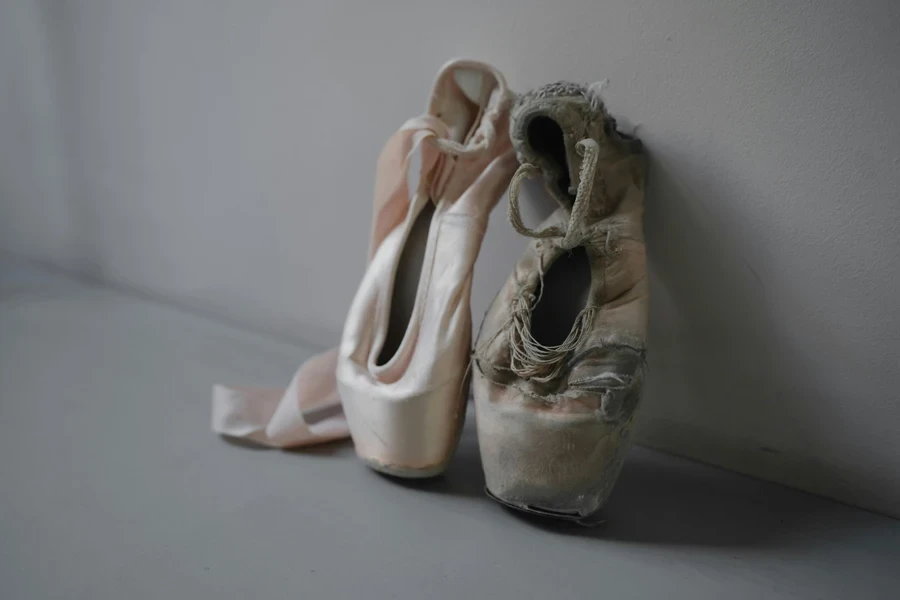 A close-up of a new and worn ballet pointe shoes symbolizing the journey of a dancer