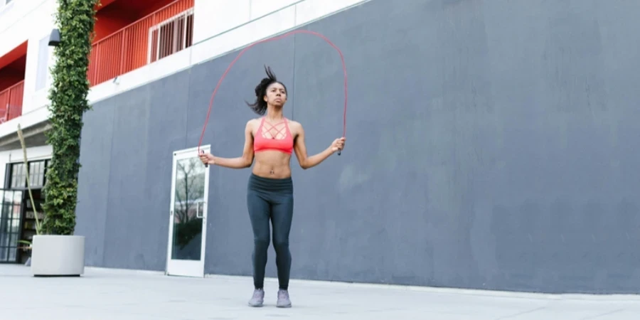 A fit woman jump ropes outdoors, showcasing a healthy and active lifestyle
