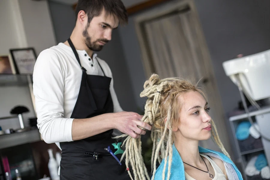 A hair stylist working on blonde locs