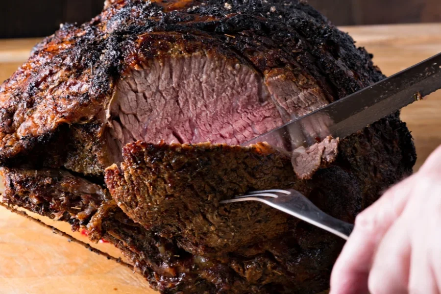 Ein langes Fleischmesser schneidet eine Neujahrs-Hochrippe