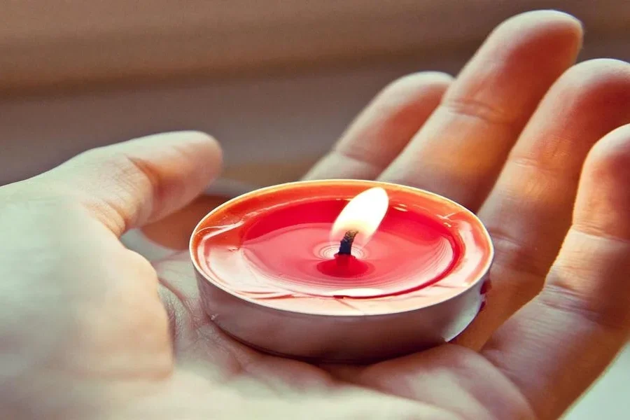 Una persona sosteniendo una vela de té encendida.