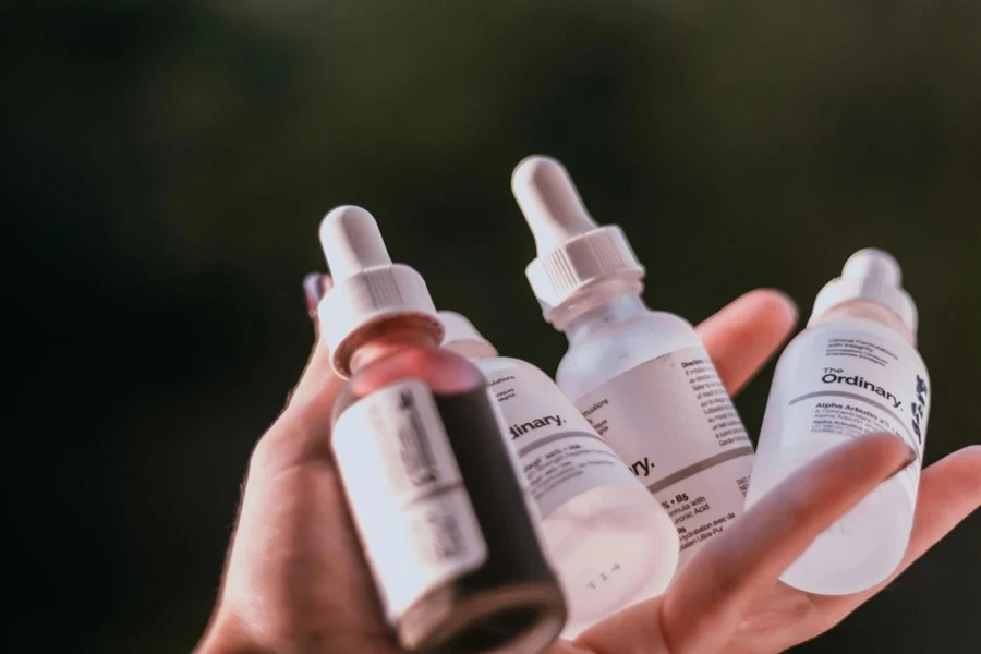 A person holding multiple glycolic acid serums in hand