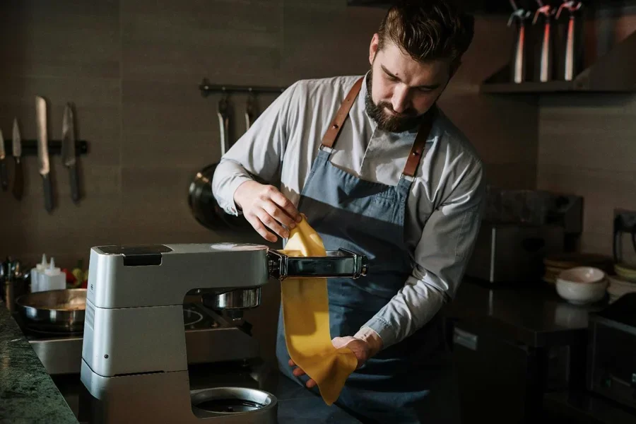 A person in an apron making pasta