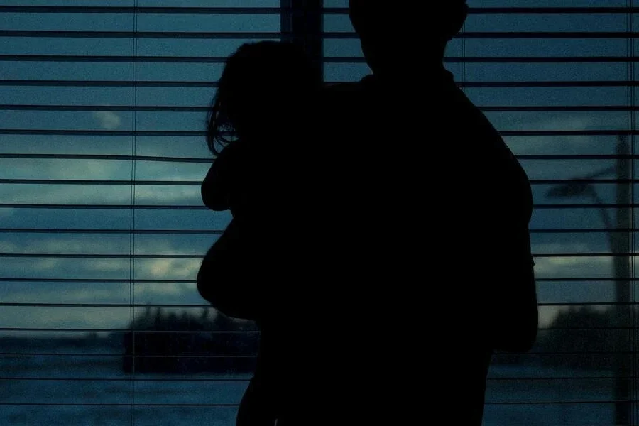 A person standing by the window carrying a child