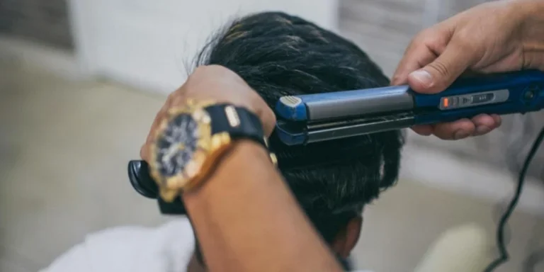 Человек, использующий утюжок для выпрямления волос