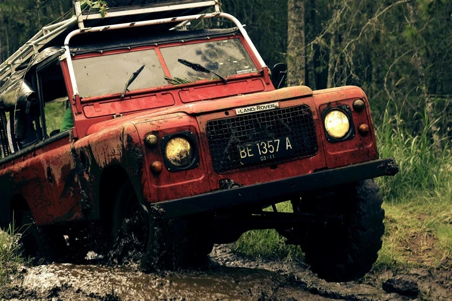 A red car driving through a muddy area