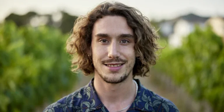 Un hombre sonriente con cabello abundante de longitud media.