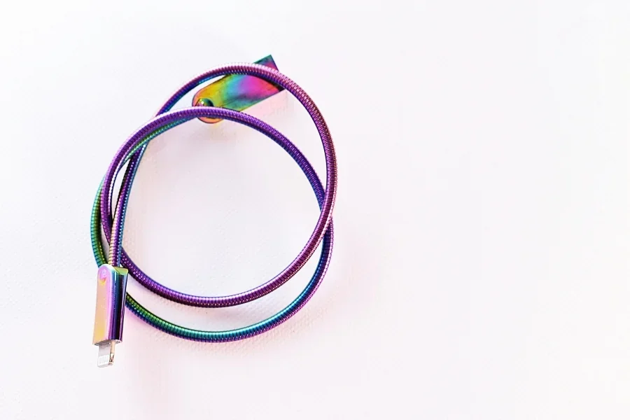 Un cable USB vibrante con colores del arco iris enrollado sobre una superficie blanca brillante