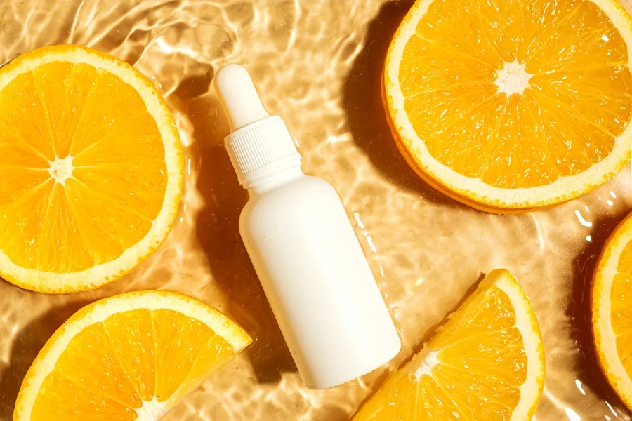 A white serum bottle and oranges in water