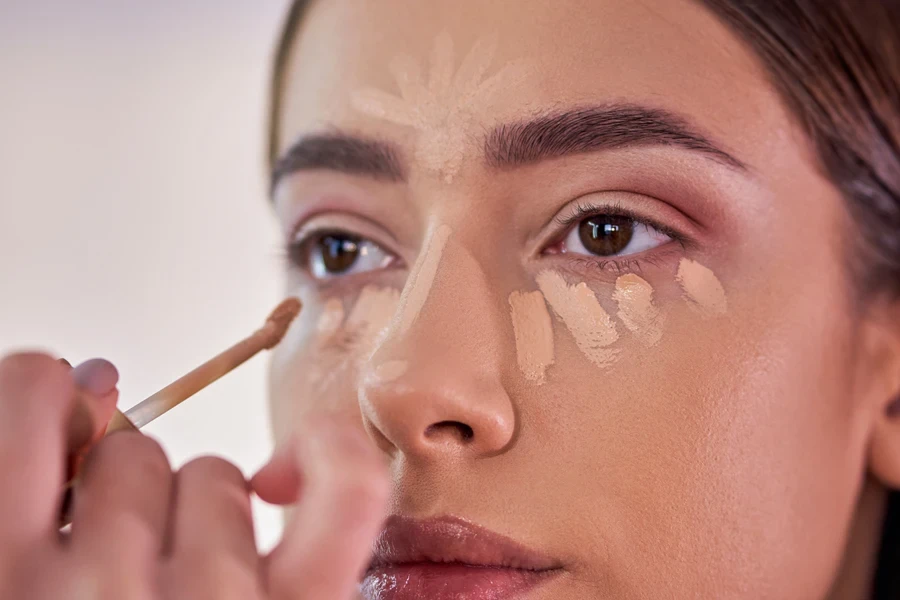 A woman applying concealer with a brush