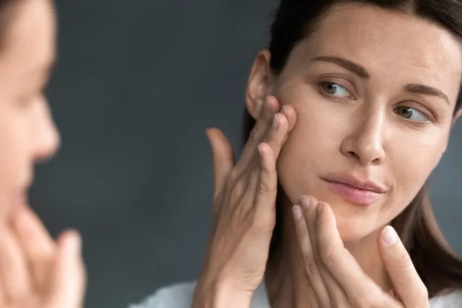 A woman applies a serum to her face