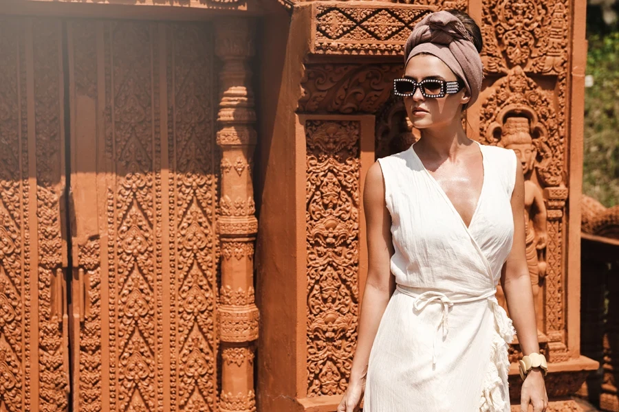 A woman posing in a white linen V-neck dress
