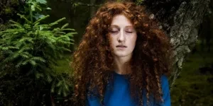 A woman with curly hair in a blue shirt