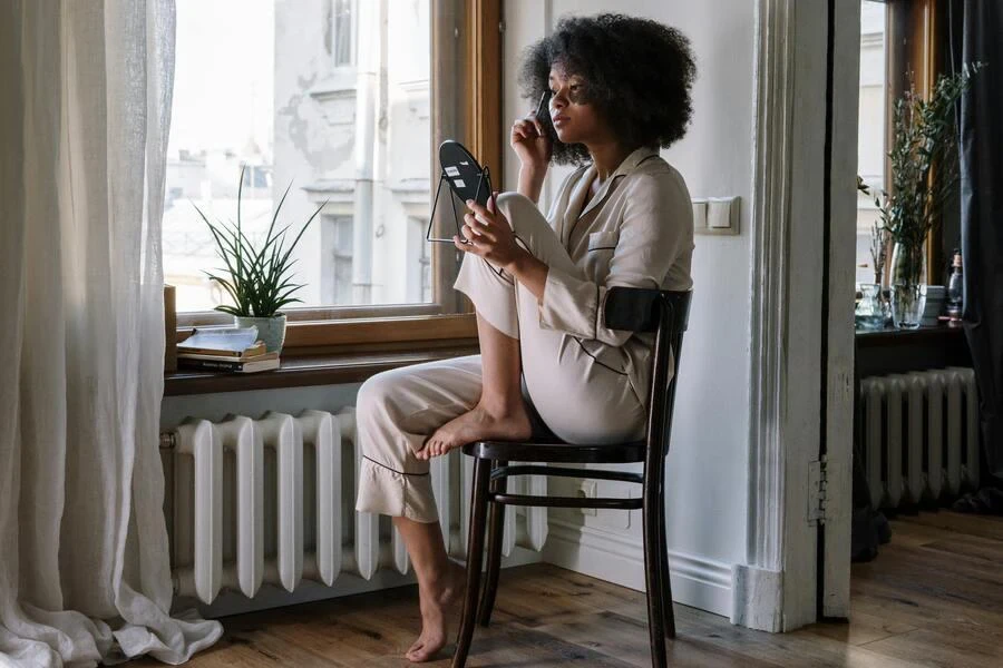 A woman with curly hair sitting near a window