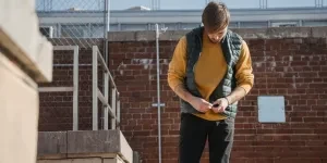 A young man in casual attire relaxes on a rooftop, exuding a calm and modern vibe