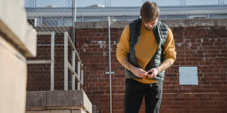 A young man in casual attire relaxes on a rooftop, exuding a calm and modern vibe