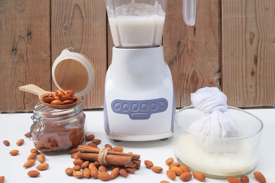 Almond nuts in a jar placed beside a nut milk maker and strainer