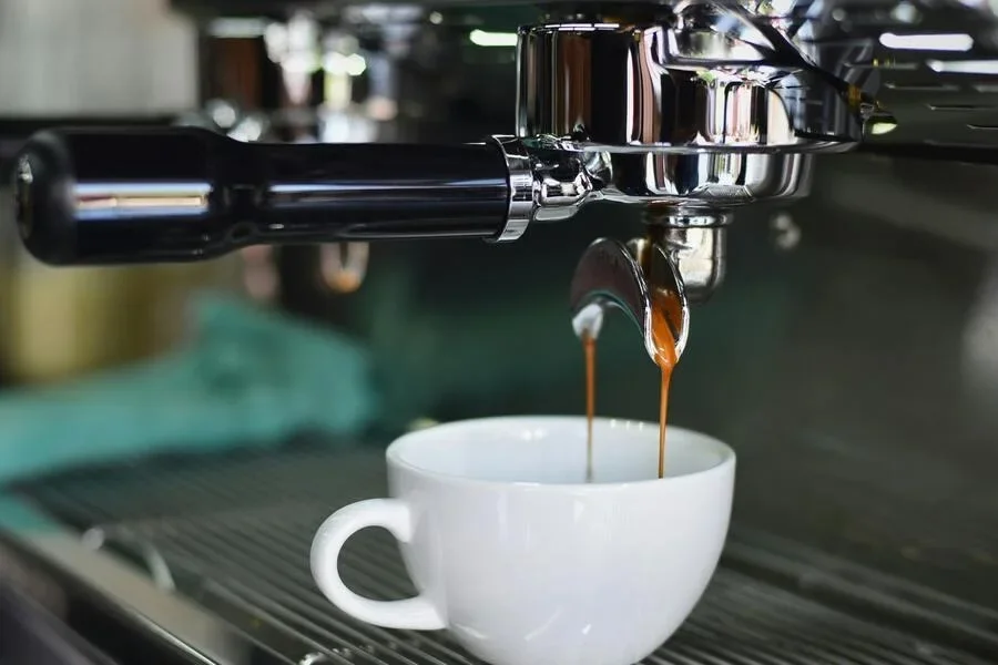 An espresso machine pouring coffee into a white mug