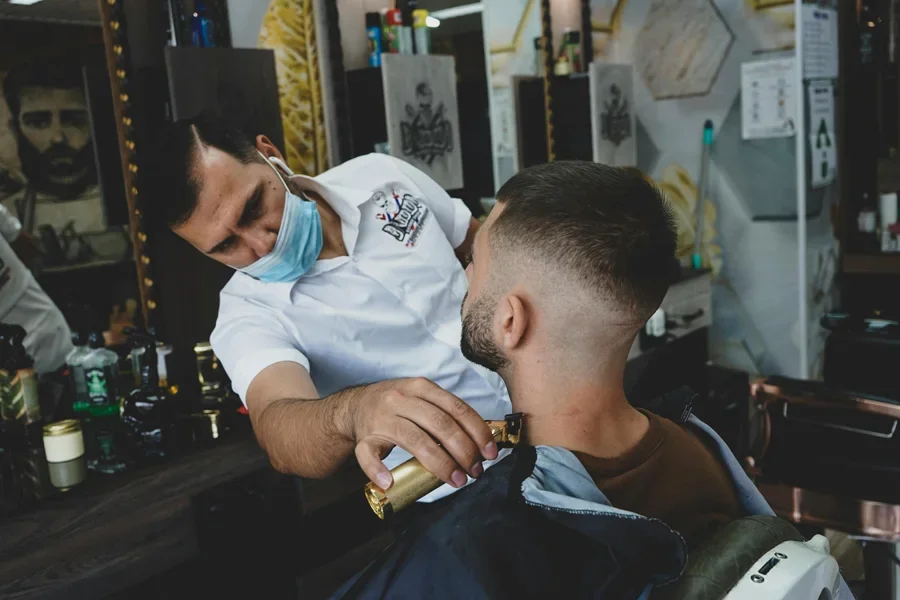 Barbero realizando un afeitado preciso con una navaja a un cliente en un entorno de barbería moderna