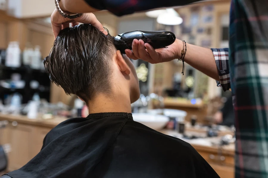 Barber using electric razor to sharpen fade lines