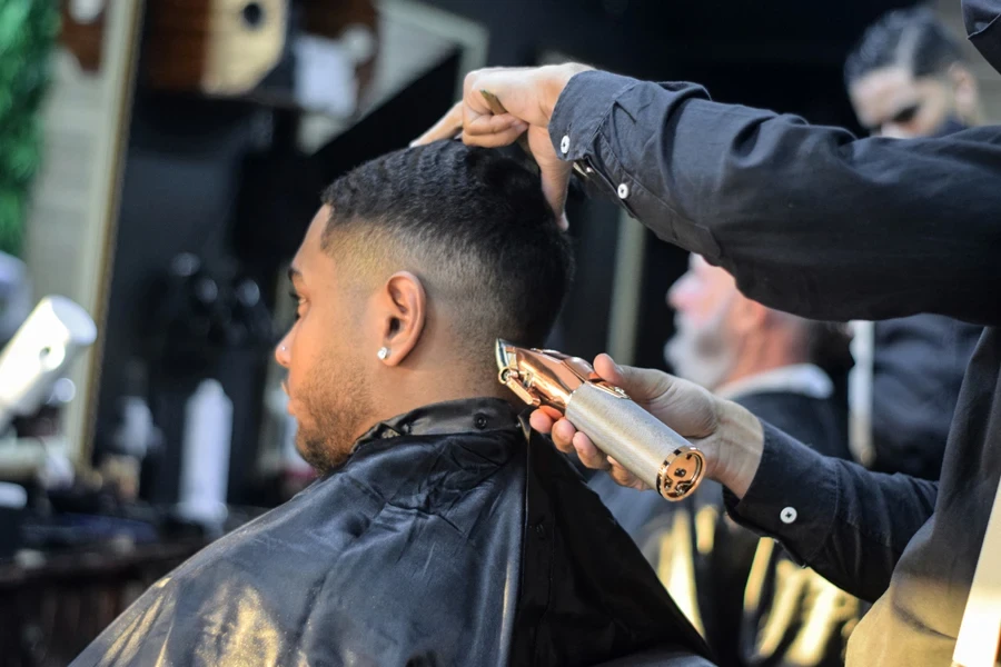 Barber with trimmer styling mid drop fade at nape