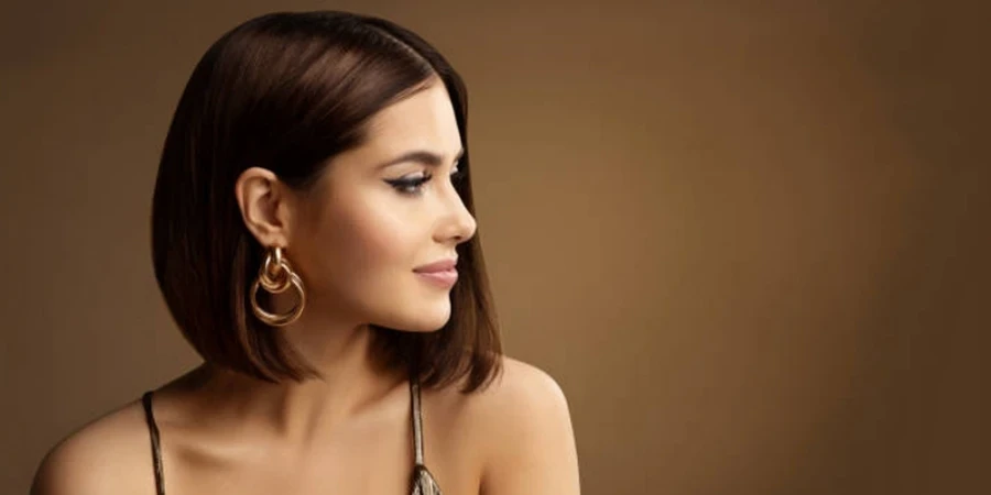 Beautiful Woman Profile Portrait with Golden Earring Bob HairStyle over dark Brown.