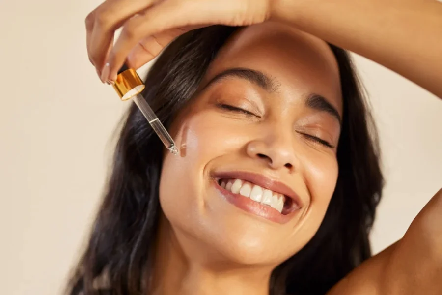 Красавица-латиноамериканка наносит сыворотку на лицо