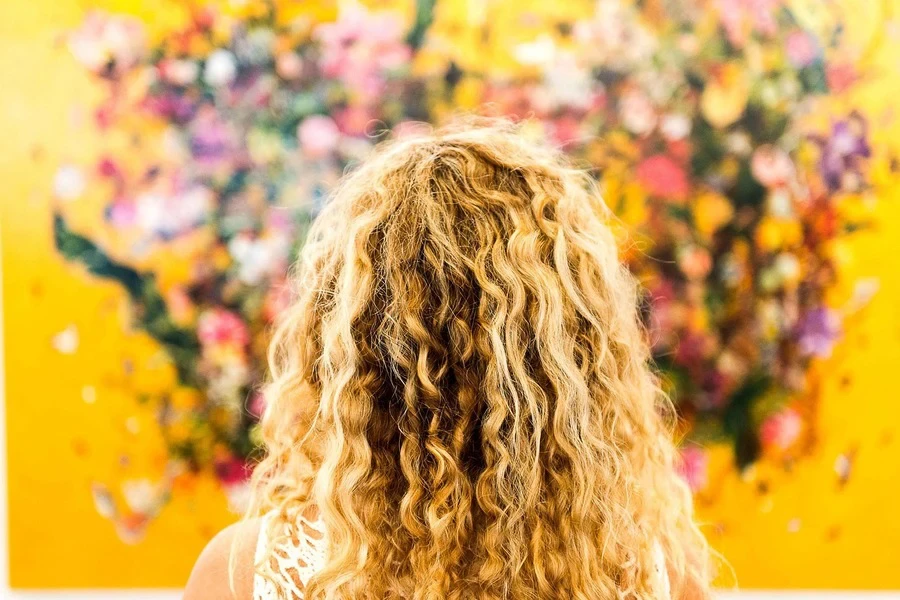 Blond-haired woman looking at a yellow wall