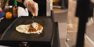 Chef preparing cheesy quesadilla on black grill