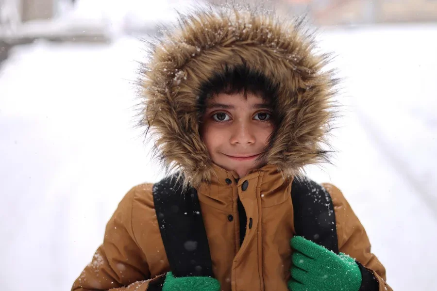 Niño caminando hacia la escuela mientras nieva