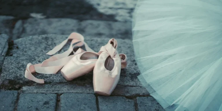 Close-up of ballet pointe shoes on cobblestone with a blue tutu, emphasizing elegance and grace