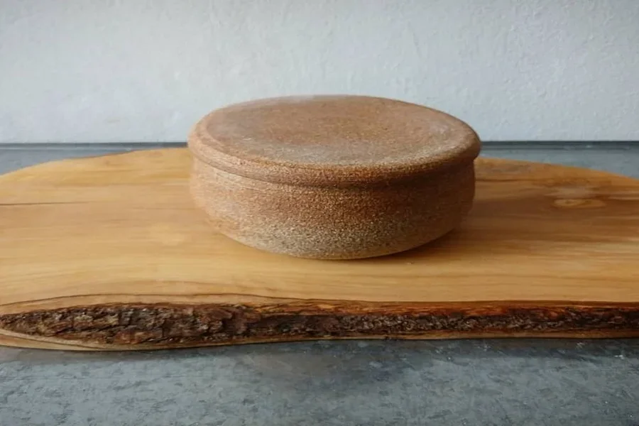 Tarro de mantequilla marrón gruesa sobre una tabla de cortar de madera