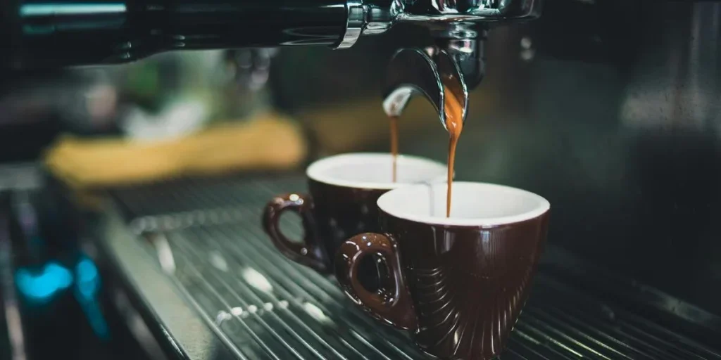 Kaffeemaschine gießt Kaffee in braune Tassen