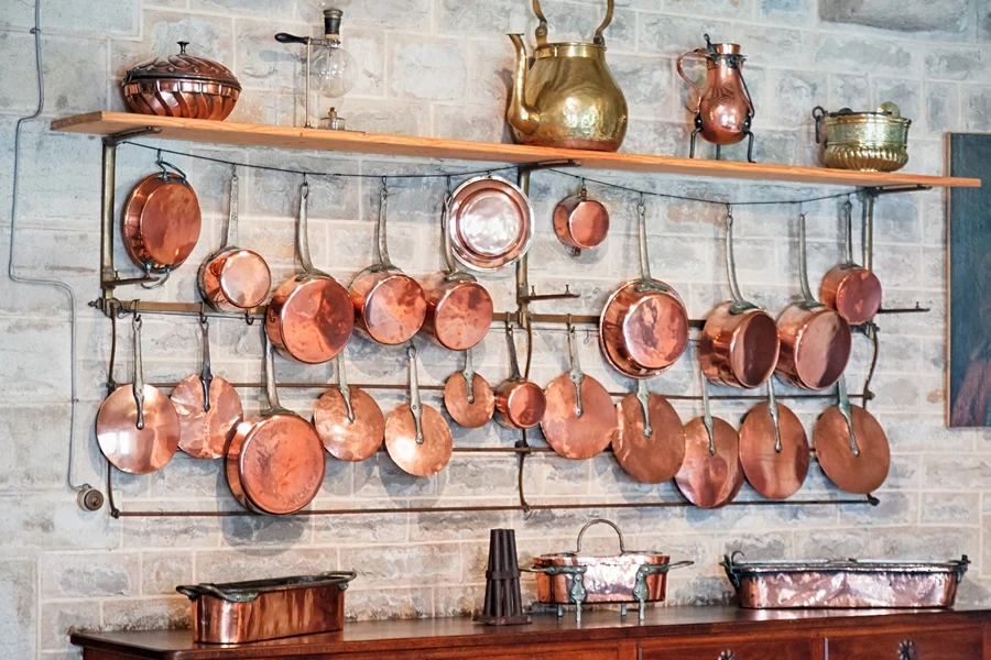 Copper pots and pans hung up on kitchen wall