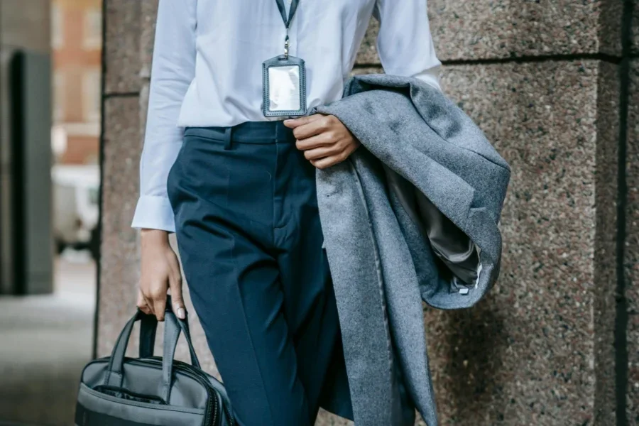 Beautiful business woman wearing coat on arm walking down city street
