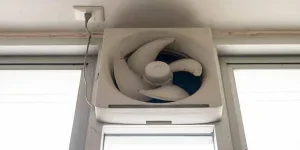 Dirty white ventilation fan on a toilet window