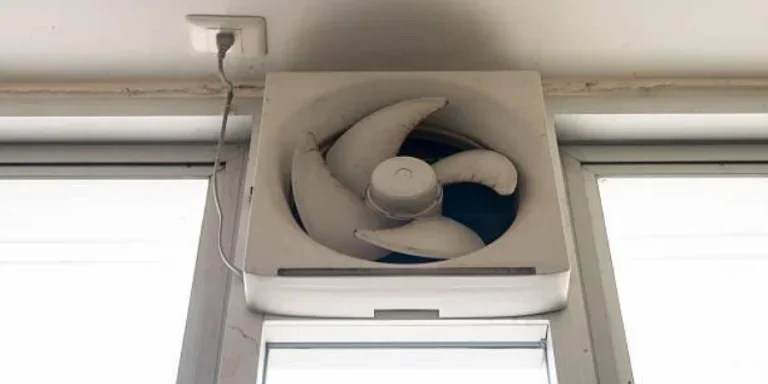 Dirty white ventilation fan on a toilet window